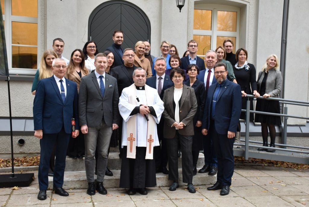 Renginio dalyviai prie atnaujinto „baltuoju mūru“ vadinamo pastato