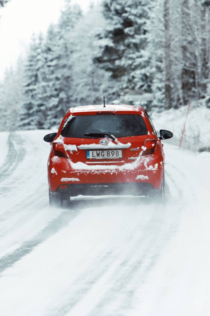 Raudonas automobilis apsnigtame kelyje