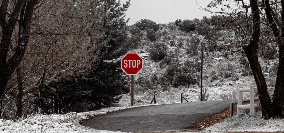 Asfaltuota gatvė, padengta sniegu su STOP ženklu