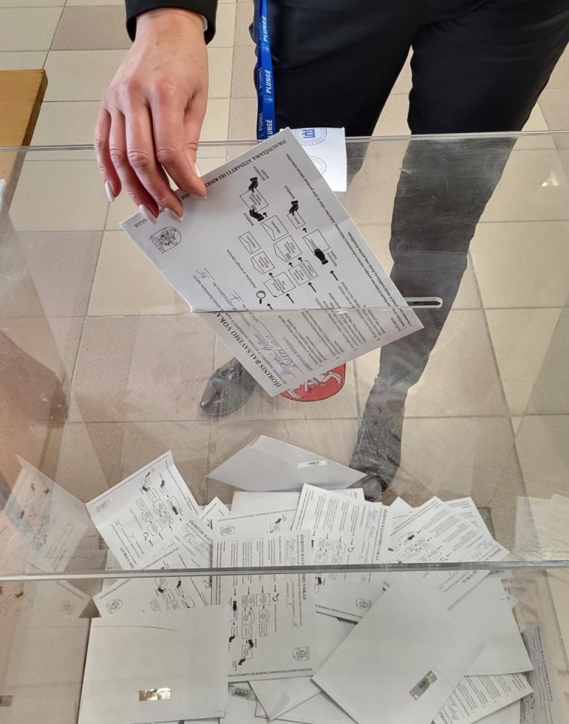 Žmogus meta balsavimo biuletenį į balsadėžę
