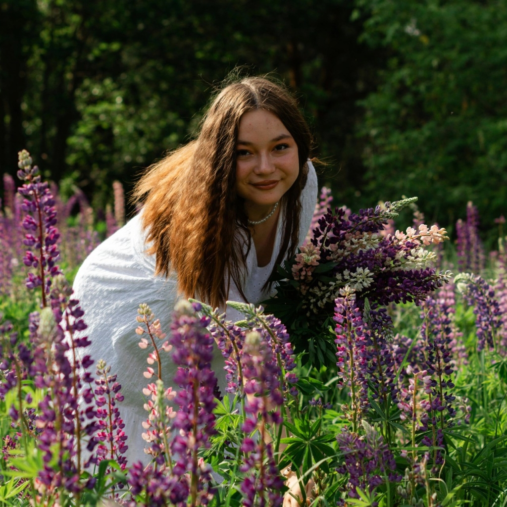 Besišypsanti moteris lubinų gėlių lauke