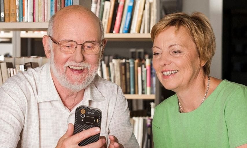 Vyras ir moteris kartu naudojasi išmaniuoju telefonu