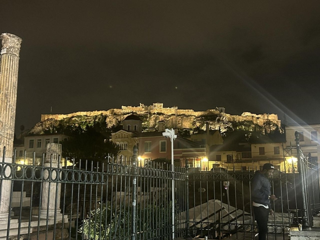 Naktis, apšviesti pastatai, kurie rikiuojasi aukštyn į viršų.