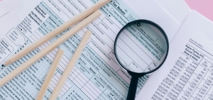 Juodas didinamasis stiklas ant atspausdintų ataskaitų