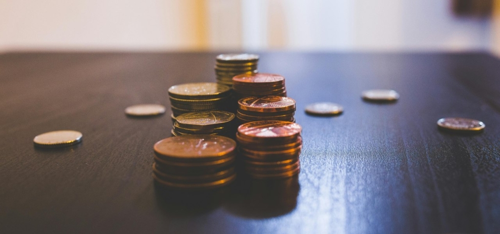 Rudų monetų krūva ant rudo medinio stalo