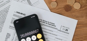 Juodas kalkuliatorius ant atspausdintų ataskaitų