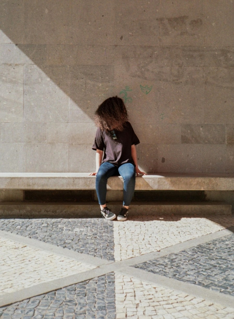 Vaikas sėdi ant betoninio suoliuko