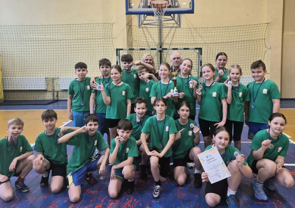 Mokiniai sporto salėje su medaliais, taure ir diplomu po varžybų.