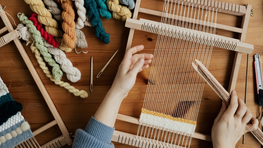 Nuotrauka iš viršaus, kurioje užfiksuotas žmogus, audžiantis rankomis