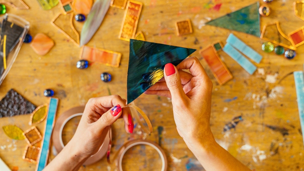 Moteris, laikanti nupjautą spalvoto stiklo gabalėlį